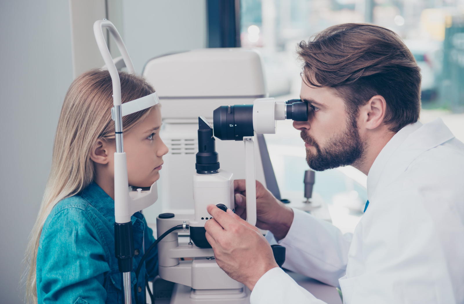 Optometrist examining young girl with a slit lamp.