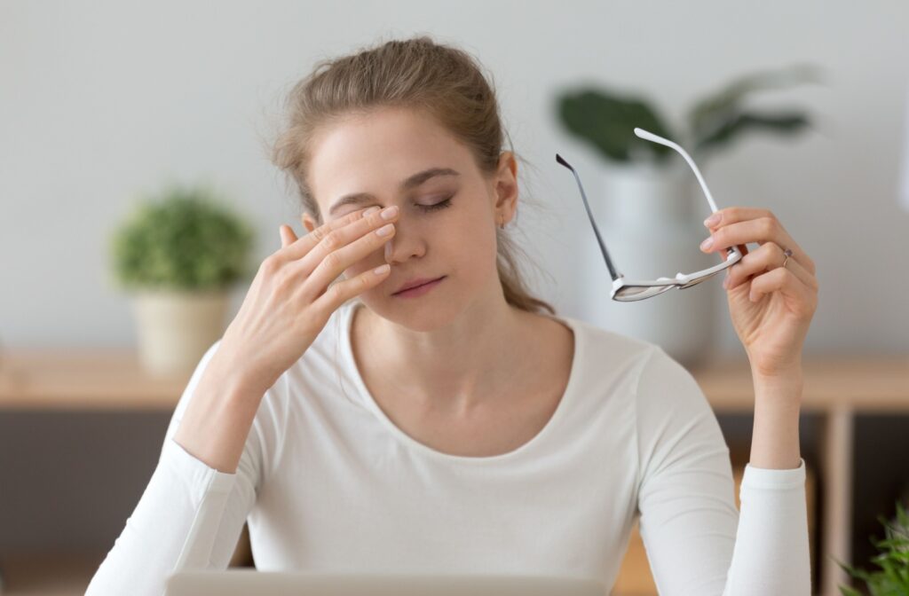 A woman experiencing dry eye syndrome rubbing her right eye.