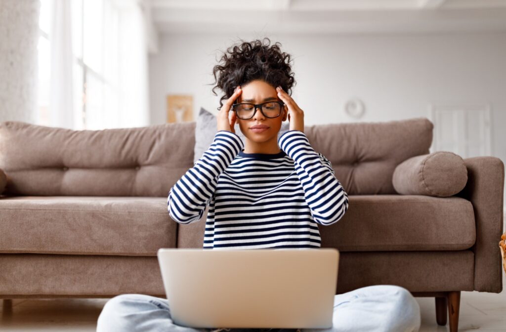 Woman at laptop rubbing her head.