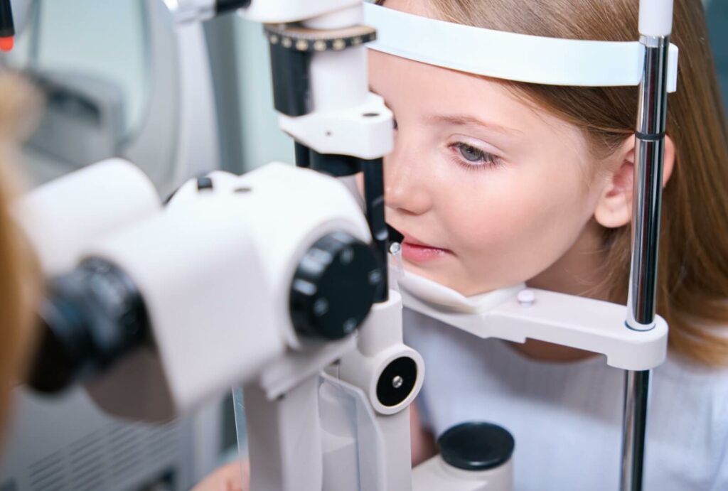 A young girl getting her eyes examined by her eye doctor at her annual children's eye exam.