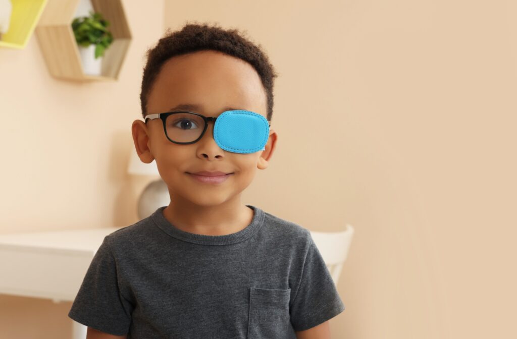 A smiling child wears a blue eye patch as part of their vision therapy program.