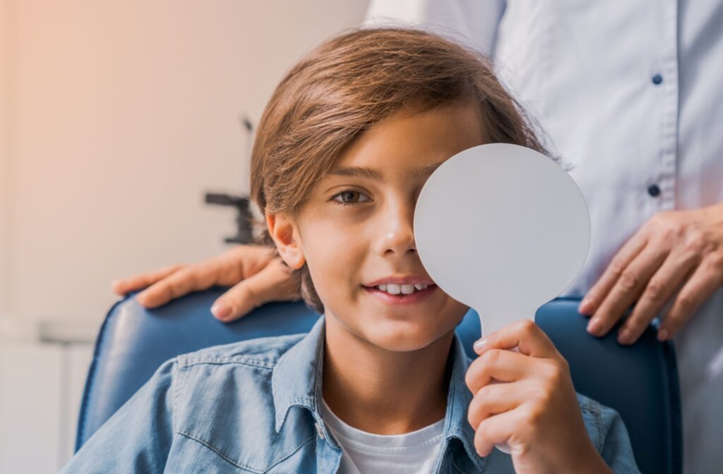 Young boy covering his left eye during an eye exam.