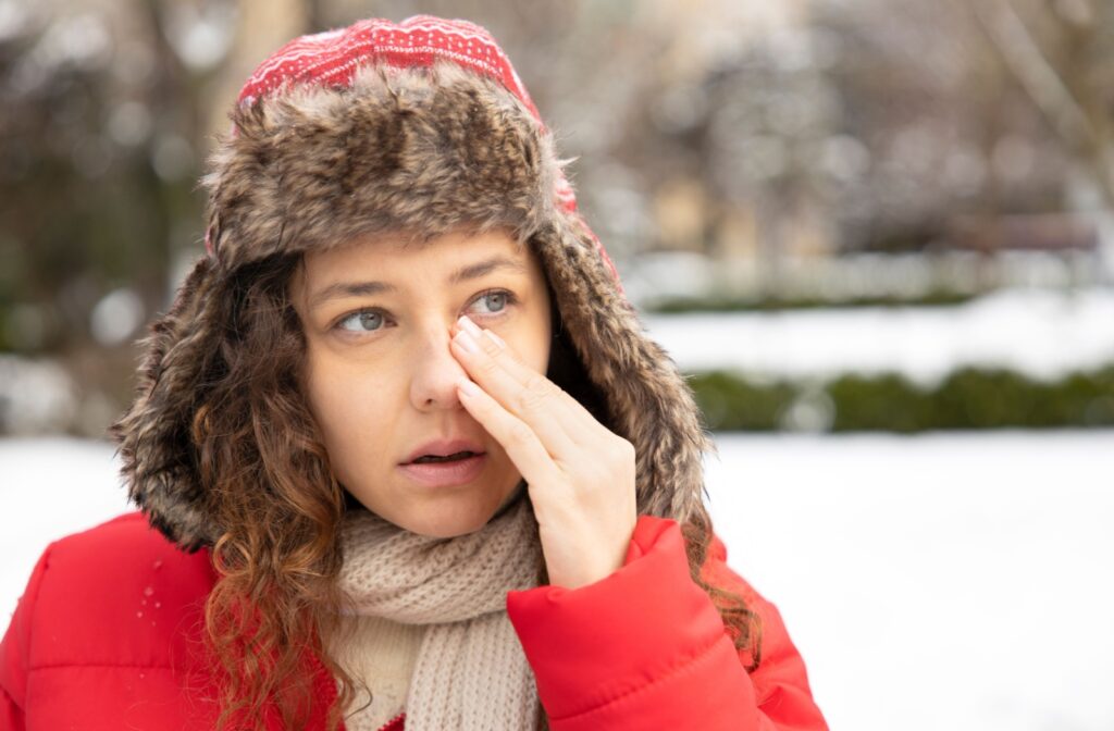 Woman outdoors with dry eyes in winter wearing a red coat and fur.